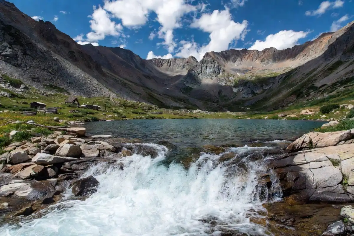 Cascading Continental Falls flowing into a clear alpine lake surrounded by rugged peaks on the Mohawk Lakes trail near Breckenridge in summer