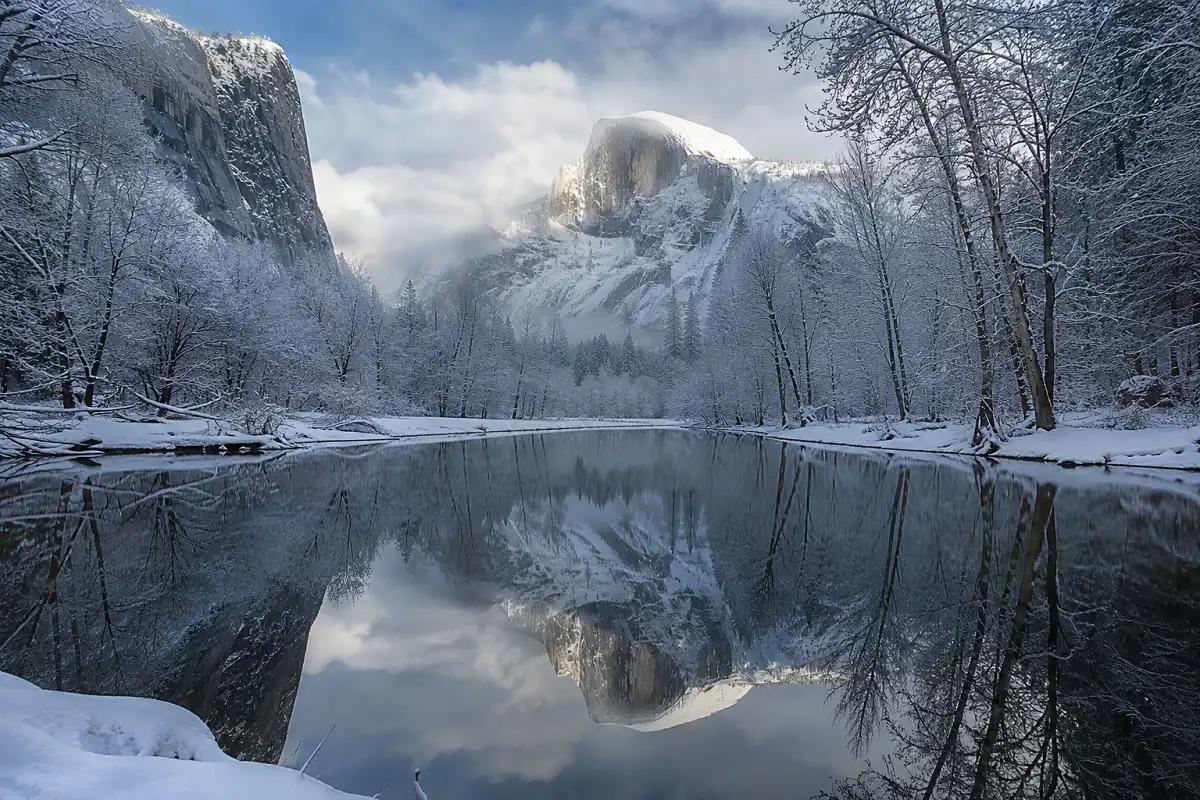 Snow dusted granite cliffs reflected in the calm winter water of Mirror Lake