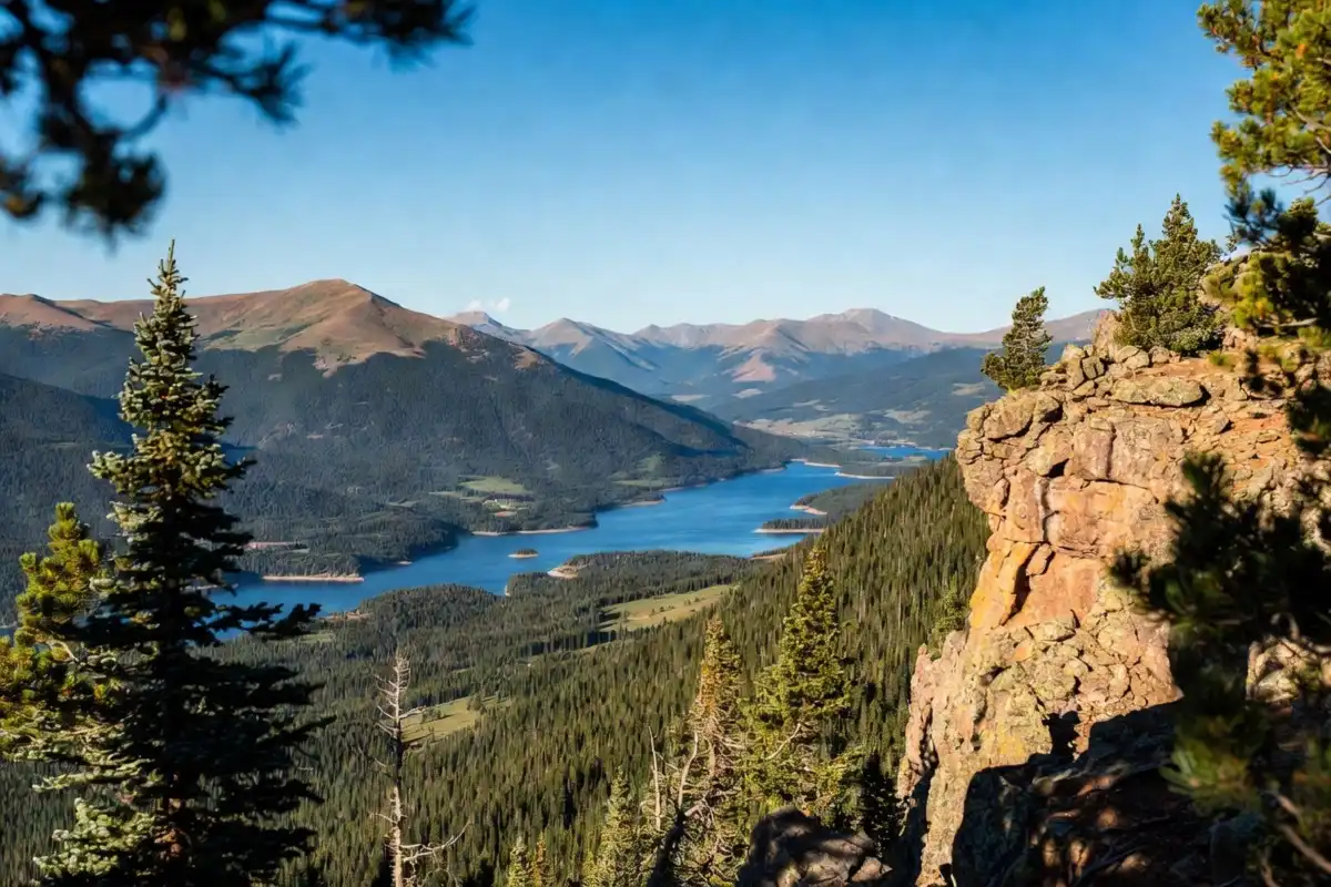 View from Sapphire Point overlook of the blue Dillon Reservoir framed by pine trees and the Gore and Tenmile mountain ranges in summer