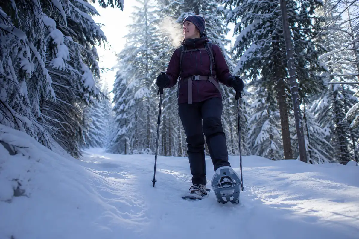 Beginner hiker snowshoeing along a flat forest trail through fresh snow