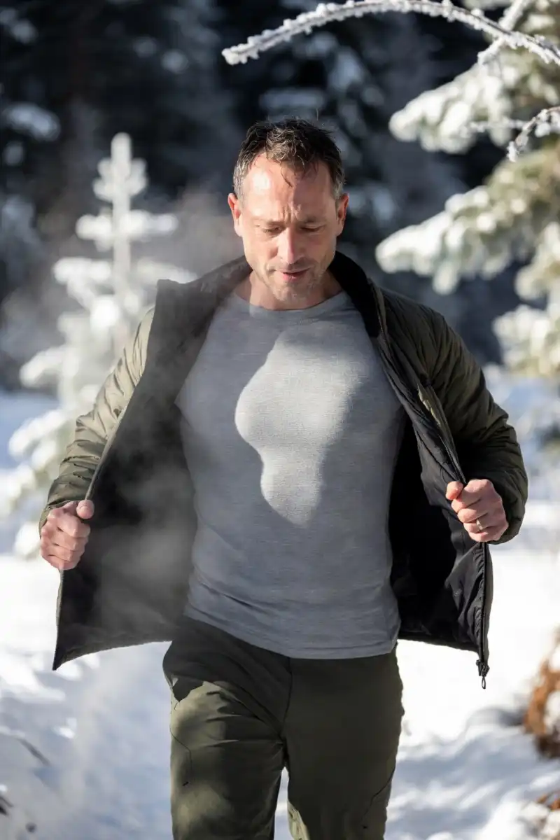 Winter hiker wearing a snug merino wool base layer that wicks moisture and keeps the body warm during a cold-weather hike.