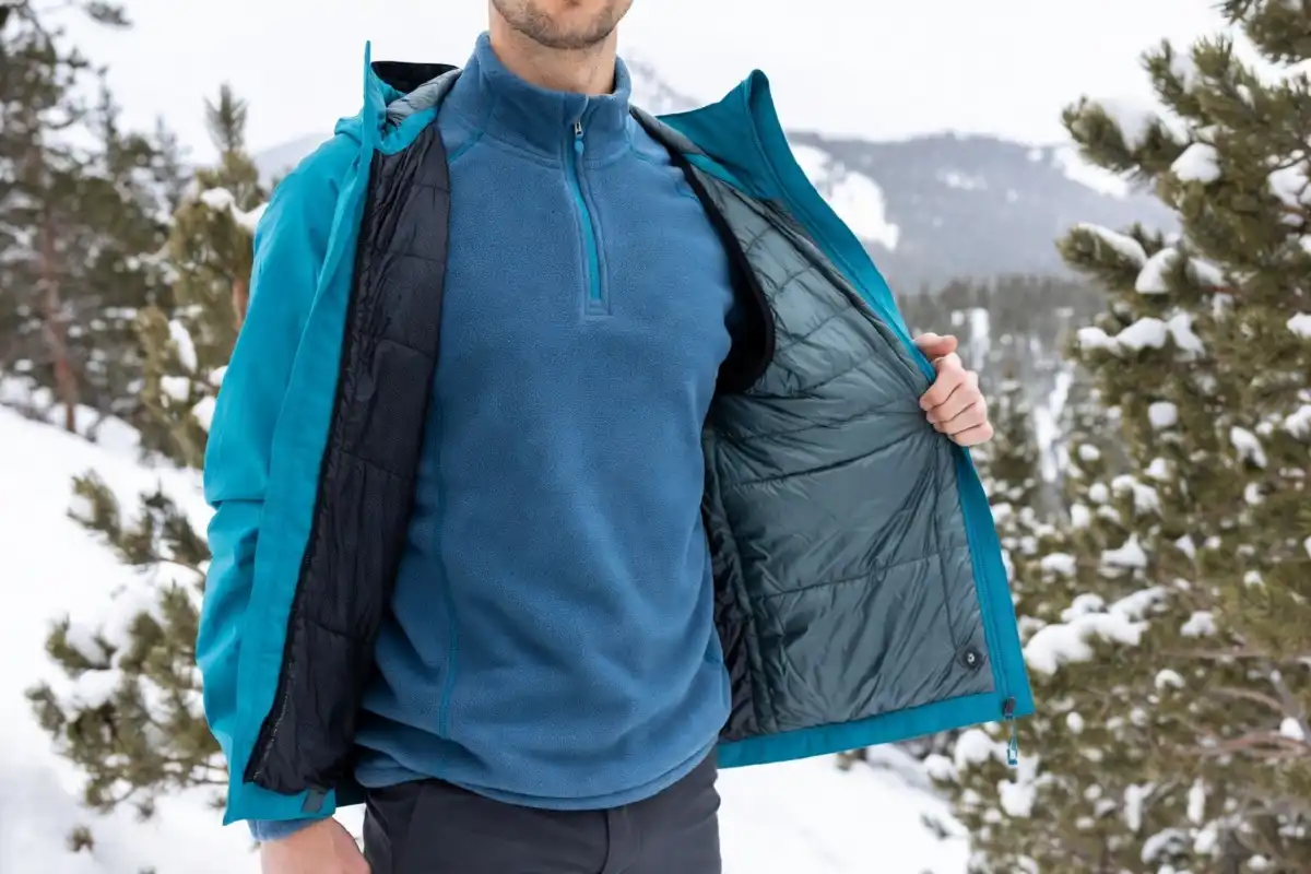 Hikers wearing fleece and insulated mid layers on a snowy winter hiking trail for warmth.