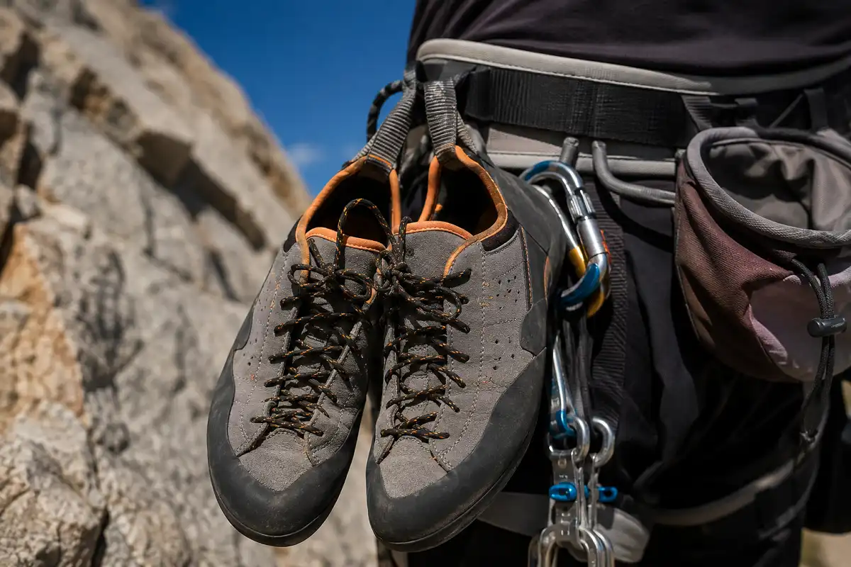 Pair of approach shoes clipped to a climbing harness during a multi-pitch climbing approach