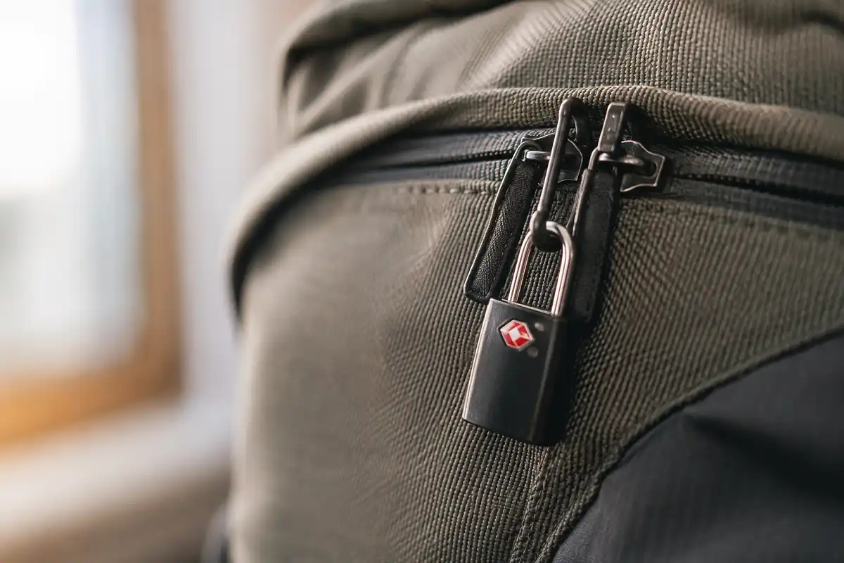 Close-up of a travel backpack's lockable zipper pulls secured with a small TSA travel lock